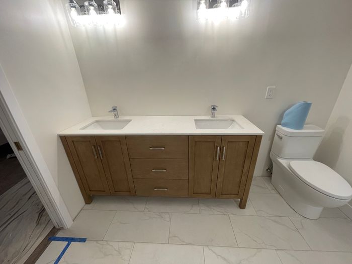 Double vanity with wood cabinet and marble tile floor