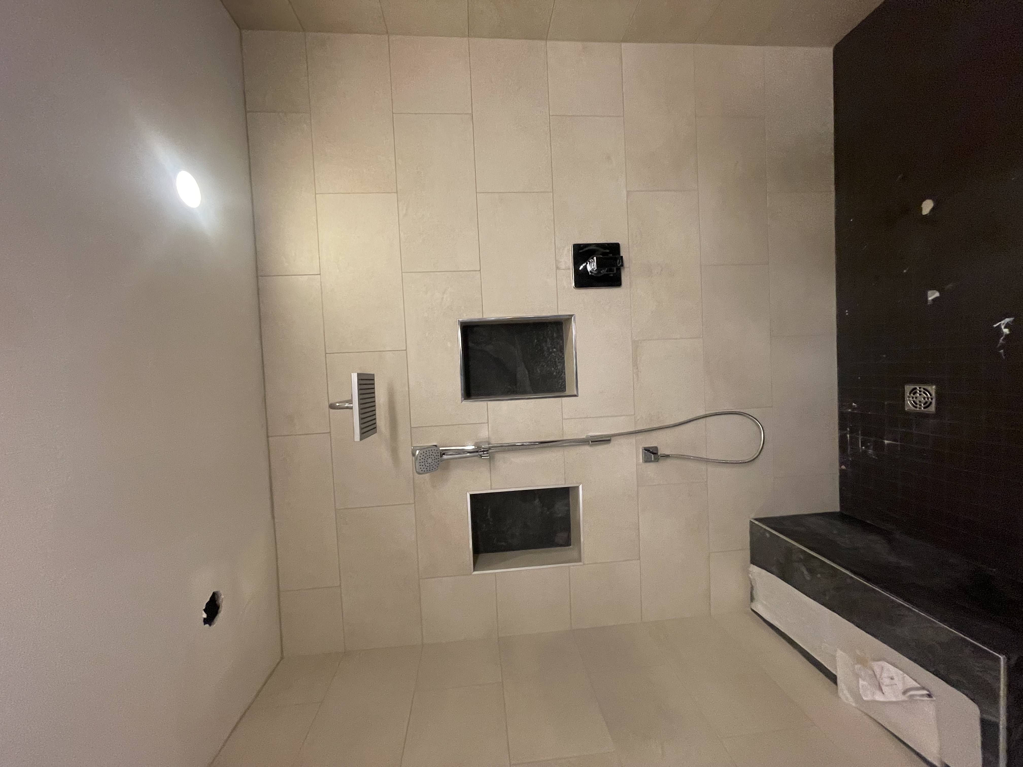 Walk-in steam shower with large-format tile, built-in niches and bench